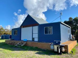 a blue and white house on a grass field at Brett's Rest Nel in Kingscote
