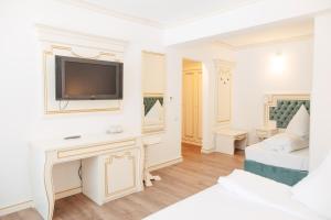 a white living room with a tv on a wall at Hotel Miruna in Sîmbăta de Sus