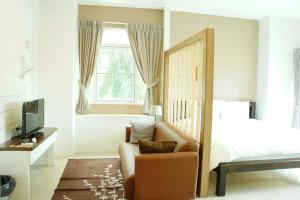 a bedroom with a bed and a chair and a television at Wealth 30th in Bangkok