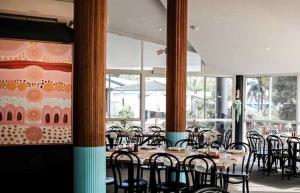 a dining room with tables and chairs and windows at The Cubana Resort Nambucca Heads in Nambucca Heads