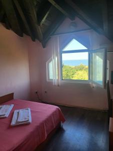 a bedroom with a red bed and a large window at Guest House Plamena in Krapets