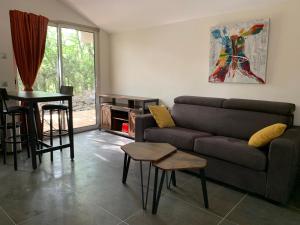 a living room with a couch and a table at Le Mazet, studio avec terrasse et spa in Saint Alban Auriolles