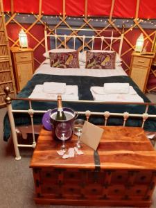 Una cama con una mesa con una botella de vino. en Orchard View Yurt & Hot Tub Somerset en Weston-super-Mare