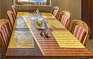 una larga mesa de madera con servilletas amarillas. en Cozy Home In Repvg With House A Panoramic View, en Repvåg