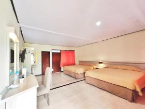 um quarto de hotel com duas camas e uma televisão em Bromo Permai 1 em Bromo