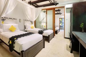 a hotel room with two beds and a television at Legian Beach Hotel in Legian