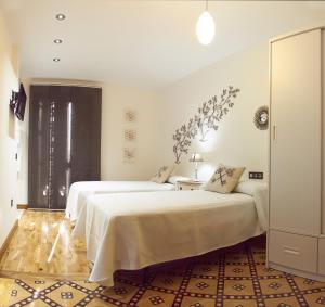 a white bedroom with two beds and a window at Hotel Rural Doña Berenguela in Bolaños de Calatrava