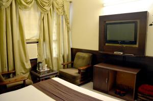 a hotel room with a bed and a tv and a chair at Hotel City Paradise in Chandīgarh
