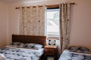 a bedroom with two beds and a window with curtains at Apollo Stay in Apollo Bay