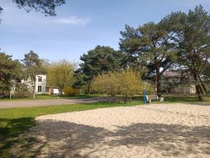un parque con un banco y árboles al fondo en Surf Apartments in Melnrage, en Klaipėda
