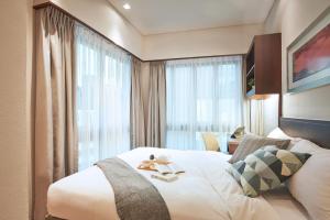 シンガポールにあるSomerset Bencoolen Singaporeの大きなベッドと窓が備わるホテルルームです。