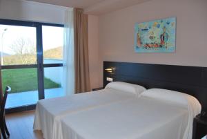 Un dormitorio con una cama blanca y una ventana grande. en Hotel Parrilla el Zangano, en Boal