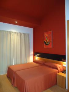 a bedroom with two beds and a red wall at Hotel Parrilla el Zangano in Boal