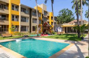 a swimming pool in front of a building with a playground at Charvi Reemz, Anjuna, Starco Junction, Goa in Anjuna