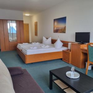 um quarto de hotel com uma cama grande e uma televisão em Müritz-Pension Waren em Waren