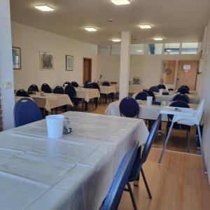 a dining room with white tables and chairs at Müritz-Pension Waren in Waren