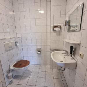 a white tiled bathroom with a toilet and a sink at Müritz-Pension Waren in Waren +13 photos