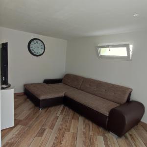 a brown couch in a room with a clock on the wall at Maison chaleureuse avec parking gratuit sur place in Coulogne