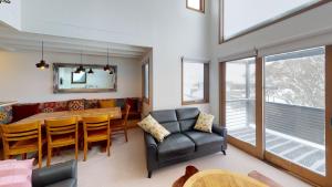 Family Chalet 35 - The Stables Perisher في بريشر فالي: غرفة معيشة مع طاولة وكراسي وغرفة طعام