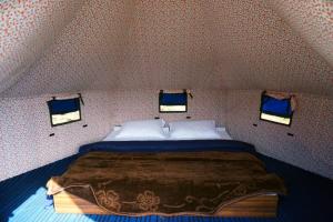 a large bed in a room with two windows at Crazy Cub Camp in Bīr +1 photo
