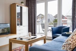 sala de estar con sofá azul y TV en Stranddomizil 8, en Kellenhusen