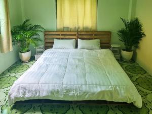 uma cama grande num quarto com duas plantas em JENI Homestay โฮมสเตย์หลังใหญ่ปิ้งย่างได้ em Ko Chang