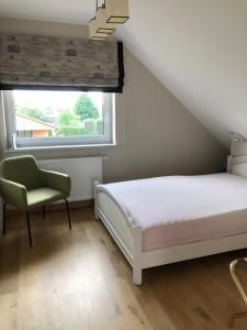 a bedroom with a bed and a chair and a window at Apartament na Podlasiu in Mielnik