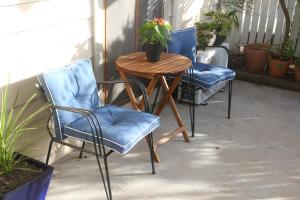 twee blauwe stoelen en een houten tafel op een patio bij Elendar Morpeth Circa 1890 in Morpeth