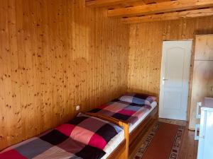 two beds in a room with wooden walls at Gábor Magánszállás Nagykanizsa Alkotmány út 195 in Palin +3 photos