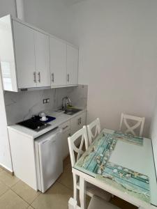 a kitchen with white cabinets and a table and a table and chairs at Hotel Mira Mare in Ksamil