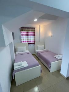 two beds in a room with purple sheets and a window at Hotel Mira Mare in Ksamil