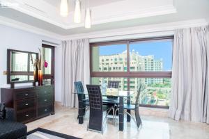 una sala da pranzo con tavolo, sedie e una grande finestra di bnbmehomes - Beach&Pool - Fairmont Residences - 3605 a Dubai
