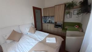 a bedroom with a white bed and a sink at Bíbic Apartman C in Kápolnásnyék
