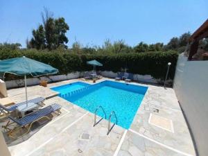 - une piscine avec 2 chaises et un parasol dans l'établissement Casa Constans, à Maleme