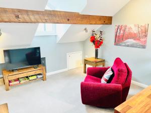 a living room with a red chair and a tv at Burley Apartment in Burley in Wharfedale