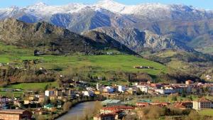 een stad met een rivier en bergen op de achtergrond bij Monte Sueve in Arriondas