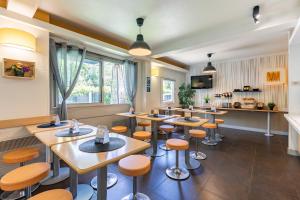 un ristorante con tavoli e sgabelli in legno di B&B HOTEL Mulhouse Dornach - Parking Gratuit a Mulhouse