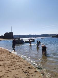 un grupo de personas en el agua en la playa en Les chambres d'hôtes du port de loguivy de la mer en Ploubazlanec