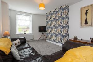 a living room with a leather couch and a tv at Nelson Street in Crook