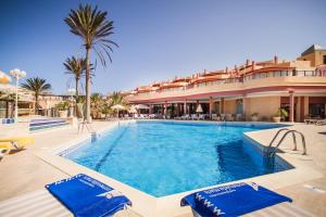 una piscina en un complejo con 2 sillas azules en Hotel Esmeralda Maris by LIVVO, en Costa Calma