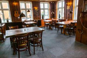 a restaurant with wooden tables and chairs and a guitar at Ansager Hotel og Hytteby in Ansager