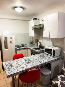 a kitchen with a counter with a microwave and red chairs at Depto 4 Metro Cal y Canto 1 dormitorio y 1baño in Santiago