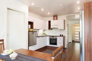 a kitchen with white cabinets and a wooden table at Holiday Villa Tonkokumpu - upea loma-asunto in Syöte