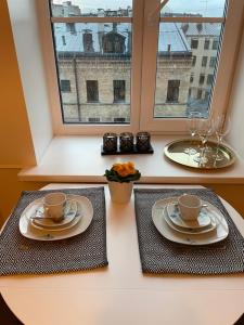 deux assiettes et tasses sur une table avec une fenêtre dans l'établissement HappyDog Lounge, à Riga