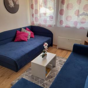 a living room with a blue couch and a table at Apartmán č. 8 Skalka in Donovaly