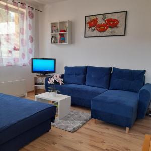 a living room with a blue couch and a tv at Apartmán č. 8 Skalka in Donovaly