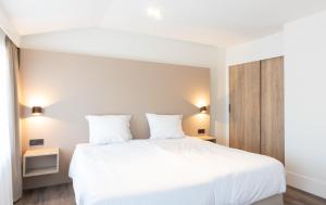 a bedroom with a large white bed with two pillows at Centrum-Appartementen Langstraat 5 in Zoutelande