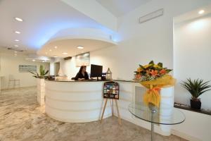 a woman sitting at a reception desk in a lobby at Hotel Diano Marina Mhotelsgroup in Diano Marina