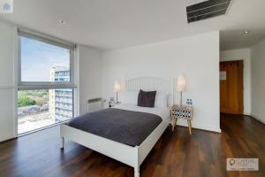 a white bedroom with a bed and a large window at London ExCeL Stays in London