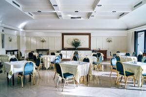 a dining room with white tables and blue chairs at Ambassador Palace Hotel in Udine